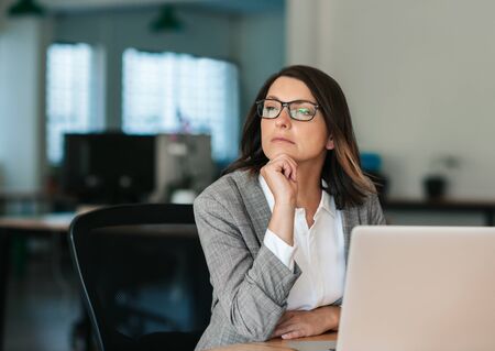 Businesswoman thinking about work while sitting at her office deskの写真素材