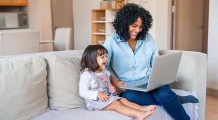 Laughing mother and little girl watching something on a laptopの写真素材