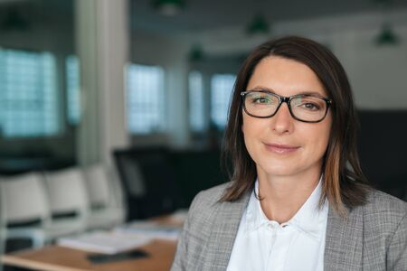 Smiling businesswoman standing by a table in an officeの写真素材