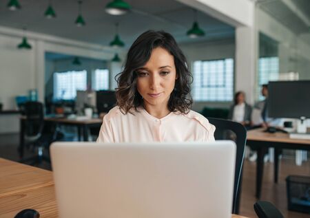 Focused young businesswoman working on her laptop in an officeの写真素材