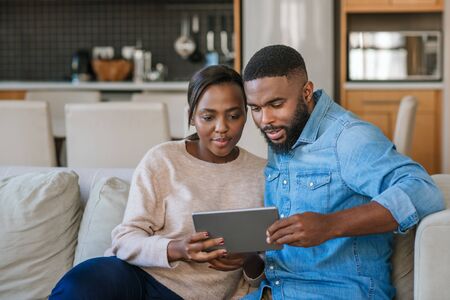 Young African American couple using a tablet together at homeの写真素材