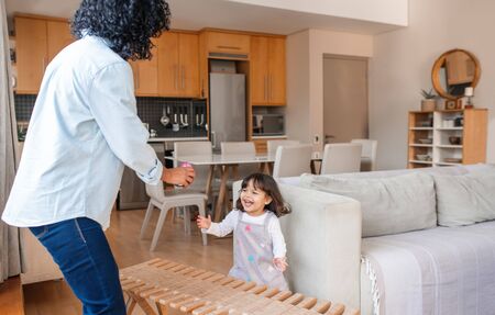 Cute little girl and her mom dancing together at homeの写真素材