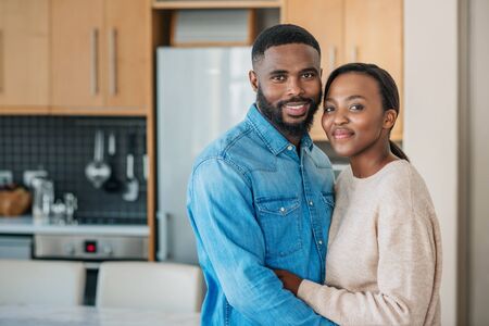 African American couple standing in each others arms at homeの写真素材