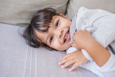 Adorable little girl playing on her living room sofaの写真素材