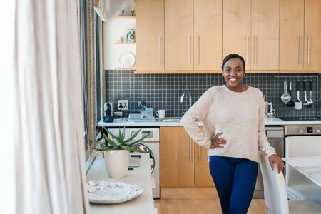 Smiling young African American woman standing in her apartmentの写真素材