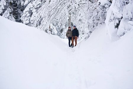 Smiling couple standing on a snow covered path while hikingの写真素材