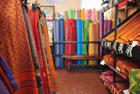 Colorful variety of printed textiles on display on racks and shelves in a fabric storeの写真素材