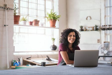 Smiling young woman using a laptop in her framing shopの写真素材