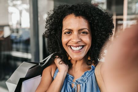 Young woman smiling and taking a selfie while out shopping