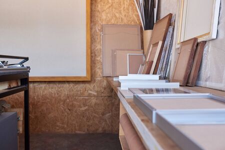 Interior of a manufacturing area of a picture framing studio with different sized frames on a workbenchの写真素材