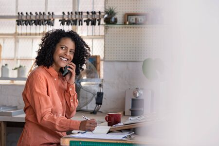 Smiling woman talking on a cellphone in her framing workshopの写真素材