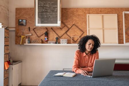 Woman working on a laptop in her picture framing shopの写真素材