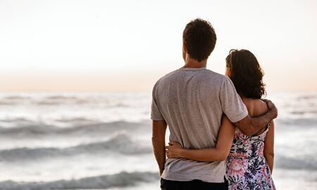 Loving young couple looking out at the ocean at sunsetの写真素材