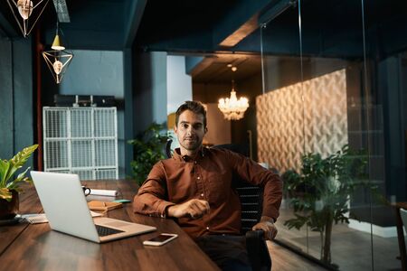 Businessman working late at his desk in a dark officeの写真素材