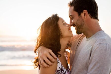 Affectionate young couple hugging on a beach at sunset
