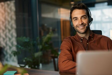 Smiling businessman talking on a headset in his office