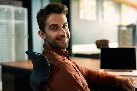 Businessman smiling while working late at his office desk