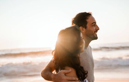 Young couple walking together by the ocean at sunsetの写真素材