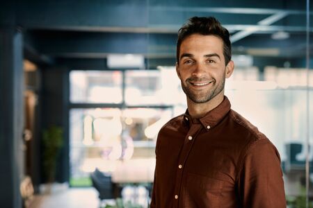 Smiling businessman working late in a dark officeの写真素材