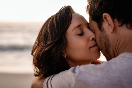 Affectionate woman standing in her husbands arms on a beach
