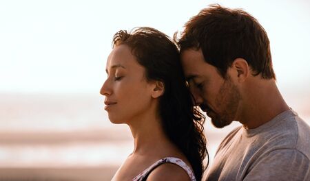 Young couple standing close together on a beach at duskの写真素材
