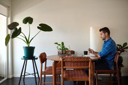 Mature man using a laptop to work remotely from homeの写真素材