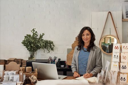 Smiling Asian woman working behind the counter of her boutiqueの写真素材