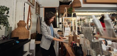 Young Asian woman working at a counter in her shopの写真素材