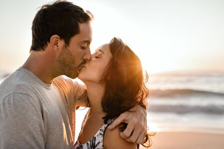 Loving young couple kissing on a beach at sunsetの写真素材