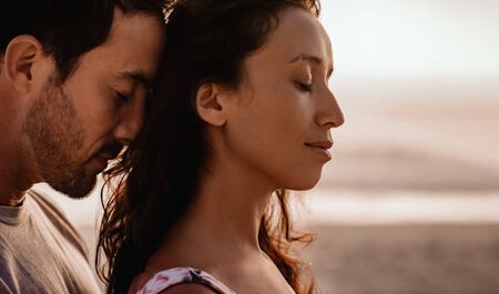 Loving couple standing close together on a beach at duskの写真素材