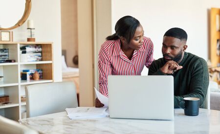 Young African American couple paying bills online with a laptopの写真素材