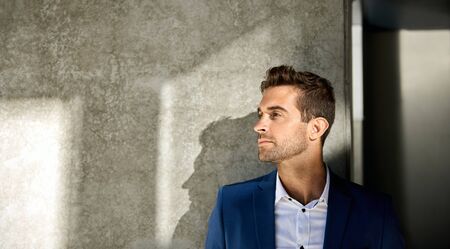 Stylish businessman standing against a pillar outside in the cityの写真素材