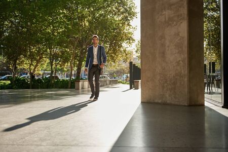 Stylish young businessman walking to work during his morning commuteの写真素材