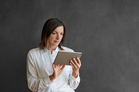 Businesswoman using a tablet in front of a blank chalkboardの写真素材