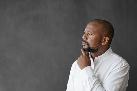 African American businessman standing by a chalkboard deep in thoughtの写真素材