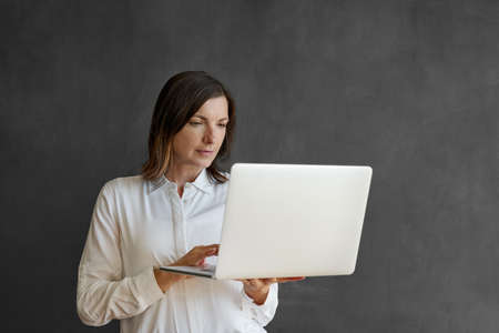 Businesswoman using a laptop in front of a blank chalkboardの写真素材
