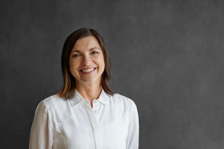 Smiling businesswoman standing in front of a blank office chalkboardの写真素材