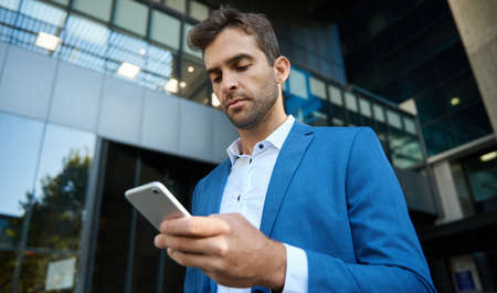 Young businessman reading a text message on his cellphoneの写真素材