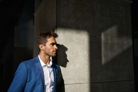 Stylish businessman leaning against a pillar outside in the city