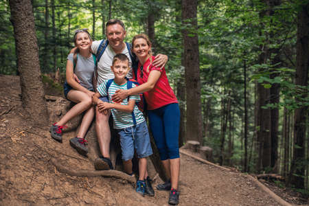 Smiling family standing together in a forest while hikingの写真素材