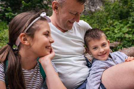 Smiling father and children taking a break from their hikeの写真素材