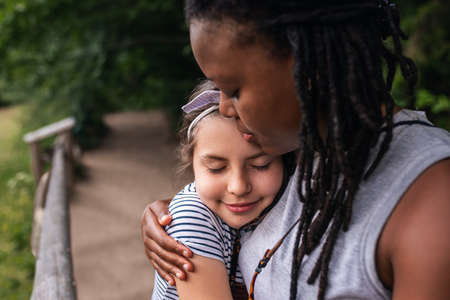 Smiling woman hugging a little girl during a hiking breakの写真素材