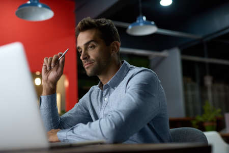 Focused young businessman working at his desk after hoursの写真素材