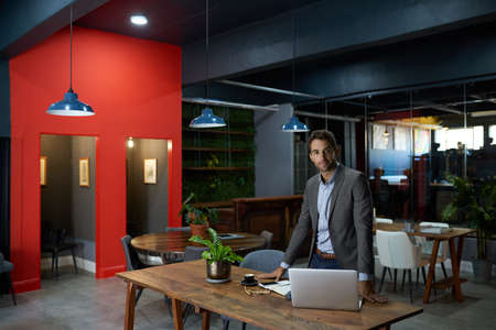 Confident businessman standing at his office desk after hours