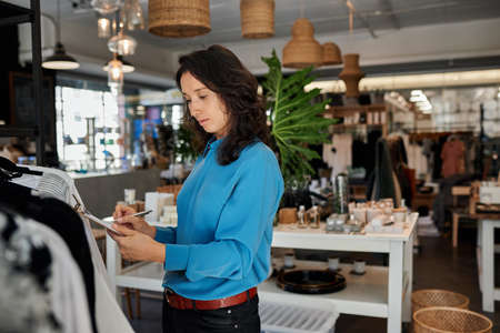 Young Asian entrepreneur doing inventory in her stylish clothing shopの写真素材