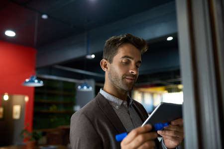 Businessman using a tablet and writing on an office whiteboardの写真素材