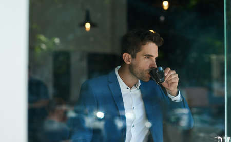 Businessman drinking a cup of coffee inside of a cafe