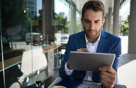 Businessman working on a tablet outside at a cafe table