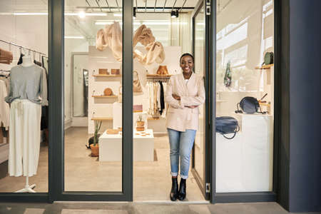 Smiling African American female entrepreneur standing at her shop door