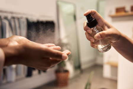 Shop assistant applying sanitizer on a customers handsの写真素材